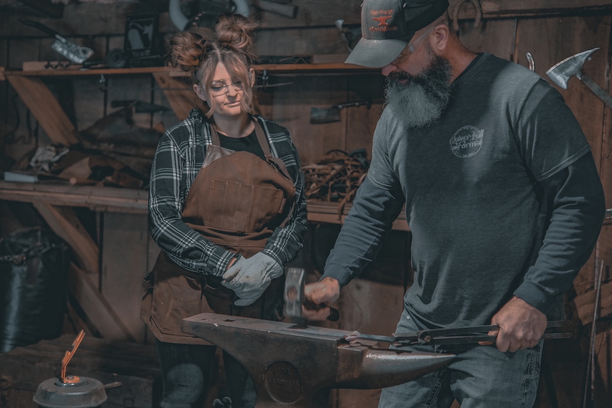 Jeremy demonstrating hammering technique to a woman at The Forge near Asheville NC